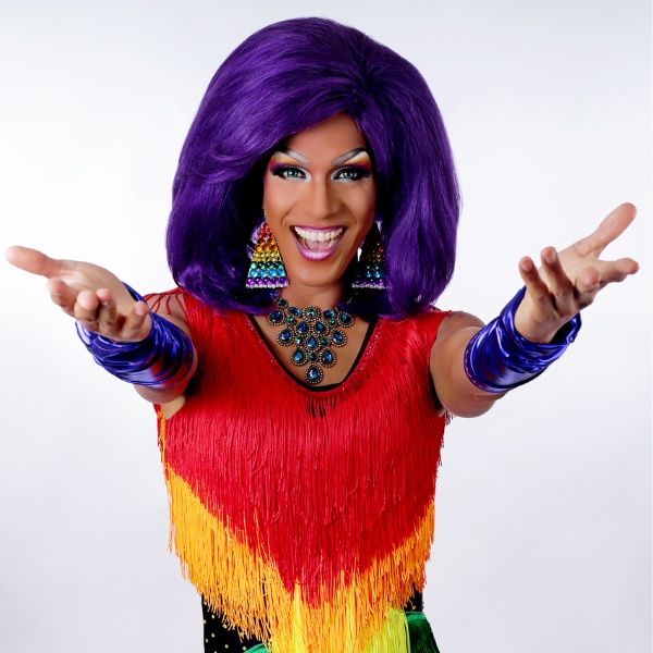 Barbada, artiste drag québécoise, accueille les voyageurs de la croisière WorldPride 2026 avec son énergie et son costume aux couleurs de l'arc-en-ciel.