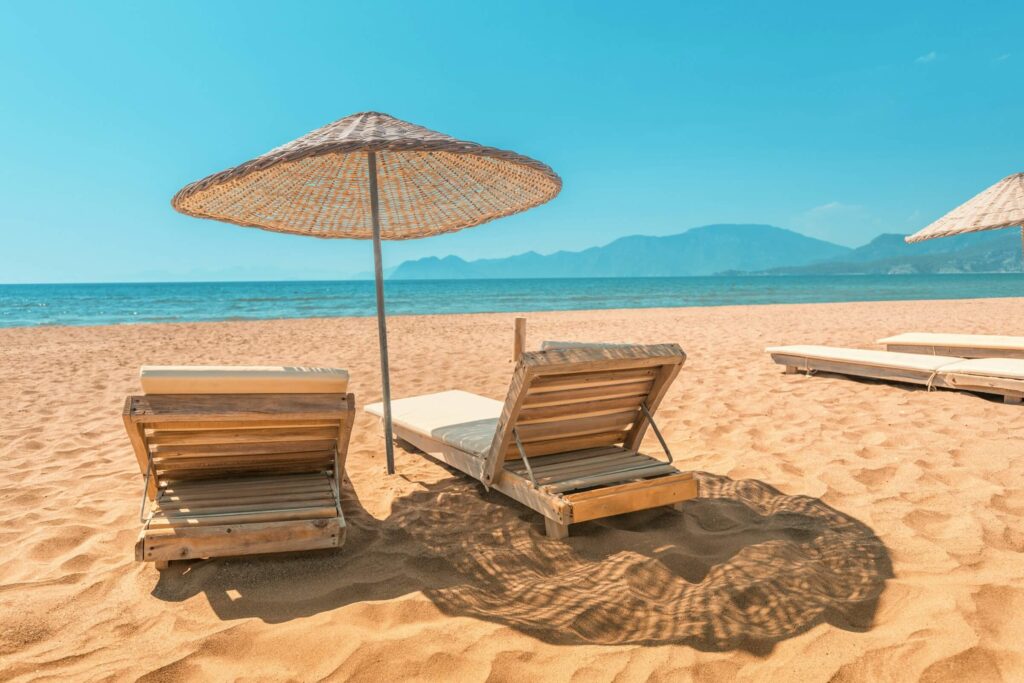 Chaises longues et parasol sur une plage face à la mer et aux montagnes
